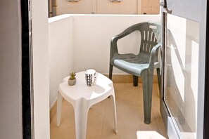 A small balcony with a white table and a green chair. There is a potted plant on the table and a mug. - Sea Breeze Bay Guesthouse - B5, Saint Paul's Bay, Malta (Saint Paul's Bay)