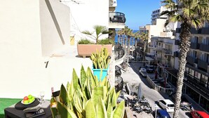 Ein Balkon mit Tisch, Pflanzen und Blick auf die Straße und die Gebäude.