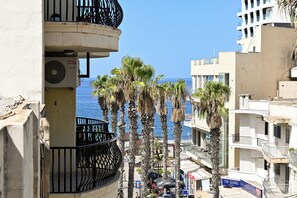 Ein Küstenabschnitt mit Hochhäusern, Palmen und freiem Blick auf das Meer.