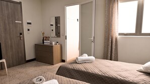 Une chambre d’hôtel avec deux lits, une commode, un miroir et une porte donnant sur la salle de bain.