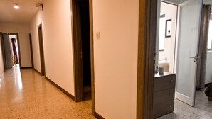 Un couloir d’hôtel avec un plancher en bois, un miroir et une porte donnant accès à une salle de bain.