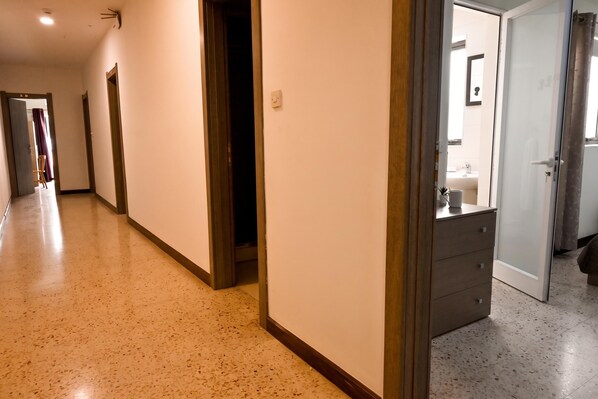 A hotel corridor with a wooden floor, a mirror, and a door leading to a bathroom. - Sea Breeze Bay Guesthouse - B2, Saint Paul's Bay, Malta (Saint Paul's Bay)