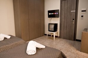 A hotel room with two beds, a wardrobe, a television, and a thermostat on the wall. - Sea Breeze Bay Guesthouse - B2, Saint Paul's Bay, Malta (Saint Paul's Bay)