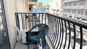 Un balcón con una mesa, una silla, una botella de champán y dos copas.