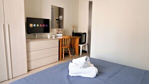 A hotel room with a bed, a desk with a computer, a television, and a mirror. - Sunny Ensuite by the Sea - B1, Saint Paul's Bay, Malta (Saint Paul's Bay)