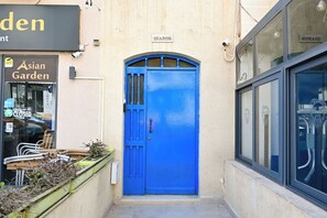 A blue door with a sign above it, a window with decorative elements, and a sign for 'Asian Garden' on the left. - Sea Breeze Bay Guesthouse - A5, Saint Paul's Bay, Malta (Saint Paul's Bay)