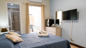 Ein Hotelzimmer mit Bett, Fernseher, Kommode und Dusche.