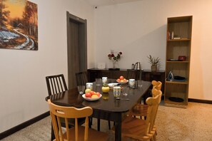 A dining area with a table set for four, chairs, a bookshelf, and a painting on the wall. - Sea Breeze Bay Guesthouse - A4, Saint Paul's Bay, Malta (Saint Paul's Bay)