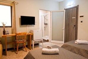 A hotel room with a bed, a desk with a chair, a TV, a shower, and a door. - Sunny Ensuite by the Sea - A3, Saint Paul's Bay, Malta (Saint Paul's Bay)