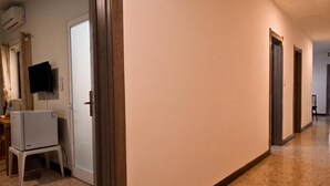 A hallway with a white door, a television mounted on the wall, and a refrigerator. - Sea Breeze Bay Guesthouse - A3, Saint Paul's Bay, Malta (Saint Paul's Bay)