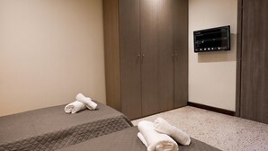 Habitación de hotel con dos camas, un armario y un panel de control digital en la pared.