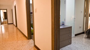 Un pasillo con piso de madera, una puerta de madera y un aparador con cajones.