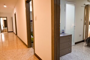 Un pasillo con piso de madera, una puerta de madera y un aparador con cajones.