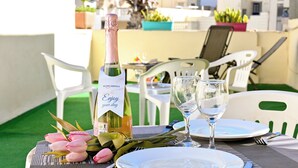 A table set with a bottle of wine, glasses, plates, and a bouquet of flowers.