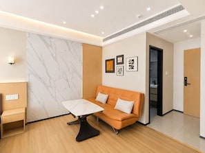 Une pièce moderne avec un mur en marbre, un canapé, une table et des œuvres d’art encadrées.