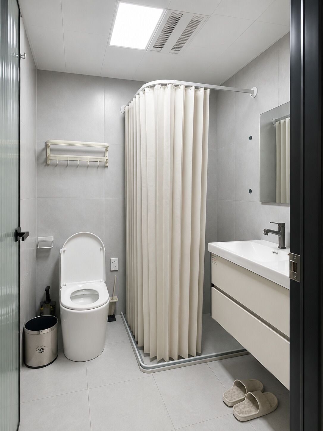 A modern bathroom with a toilet, sink, and shower curtain.
