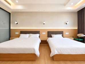 A hotel room with two beds, a wooden floor, and a modern design.