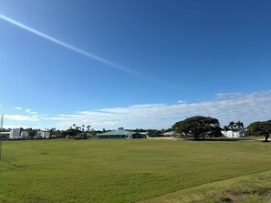 A large open grassy field with buildings in the background.