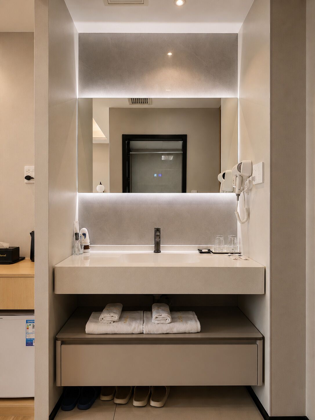 A modern bathroom with a large mirror, a sink, a towel rack, and a hairdryer.