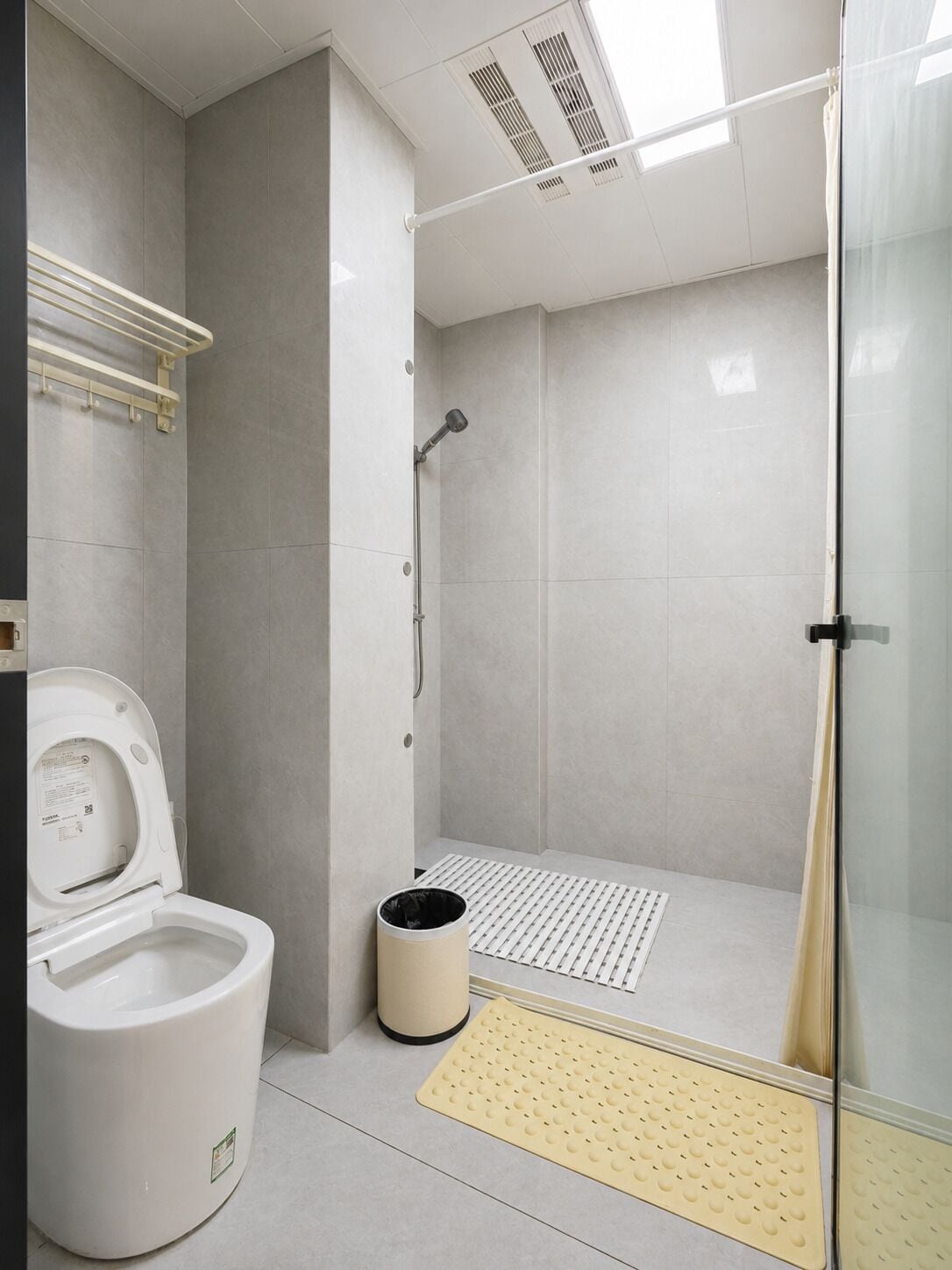 A modern bathroom with a toilet, shower, and a glass partition.