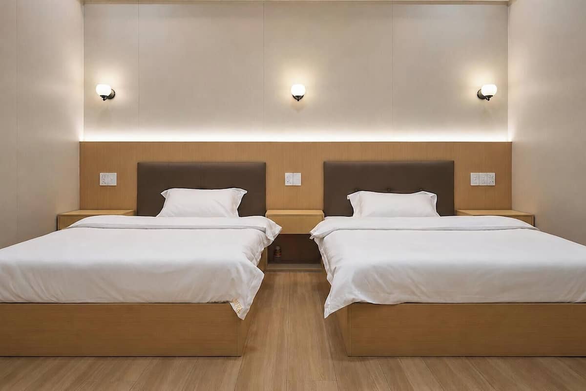 A double room with two beds, wooden headboards, and wall-mounted light fixtures.