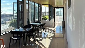 A modern interior with a long corridor, large windows, and a dining area with chairs and tables. - Fantasy Inn (Nuku'alofa)