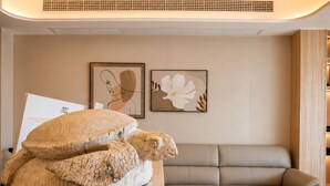 A room with a large sculpture on a table, a beige sofa, and two framed artworks on the wall. - Fantasy Inn (Nuku'alofa)