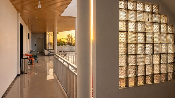 A corridor with a railing, a bench, and a window with a geometric pattern. - Fantasy Inn (Nuku'alofa)