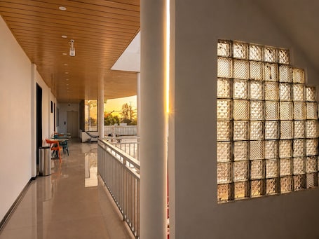 A corridor with a railing, a bench, and a window with a geometric pattern.. Fantasy Inn