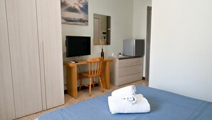 A bedroom with a bed, a desk with a computer, a chair, a television, and a wardrobe. - Sunny Ensuite by the Sea - A1, Saint Paul's Bay, Malta (Saint Paul's Bay)