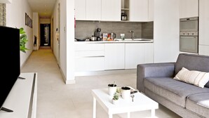 Une cuisine moderne avec des meubles blancs, un four encastré et un plan de travail équipé de divers appareils.