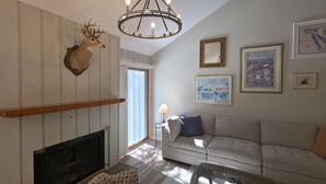 Ein Wohnzimmer mit Kamin, einer Couch, einer Deckenleuchte und Wandbildern.