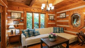 L’intérieur d’un chalet confortable, avec un canapé, une table basse et un lustre.