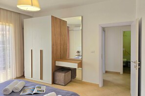 A bedroom with a bed, a wardrobe, a mirror, and a door leading to a bathroom.