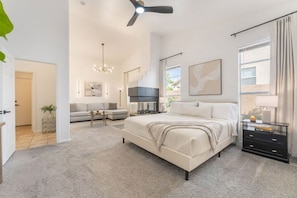 A bedroom with a bed, a sofa, a TV, and a ceiling fan.