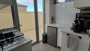 A compact kitchen with a dishwasher, a small refrigerator, and a coffee maker.