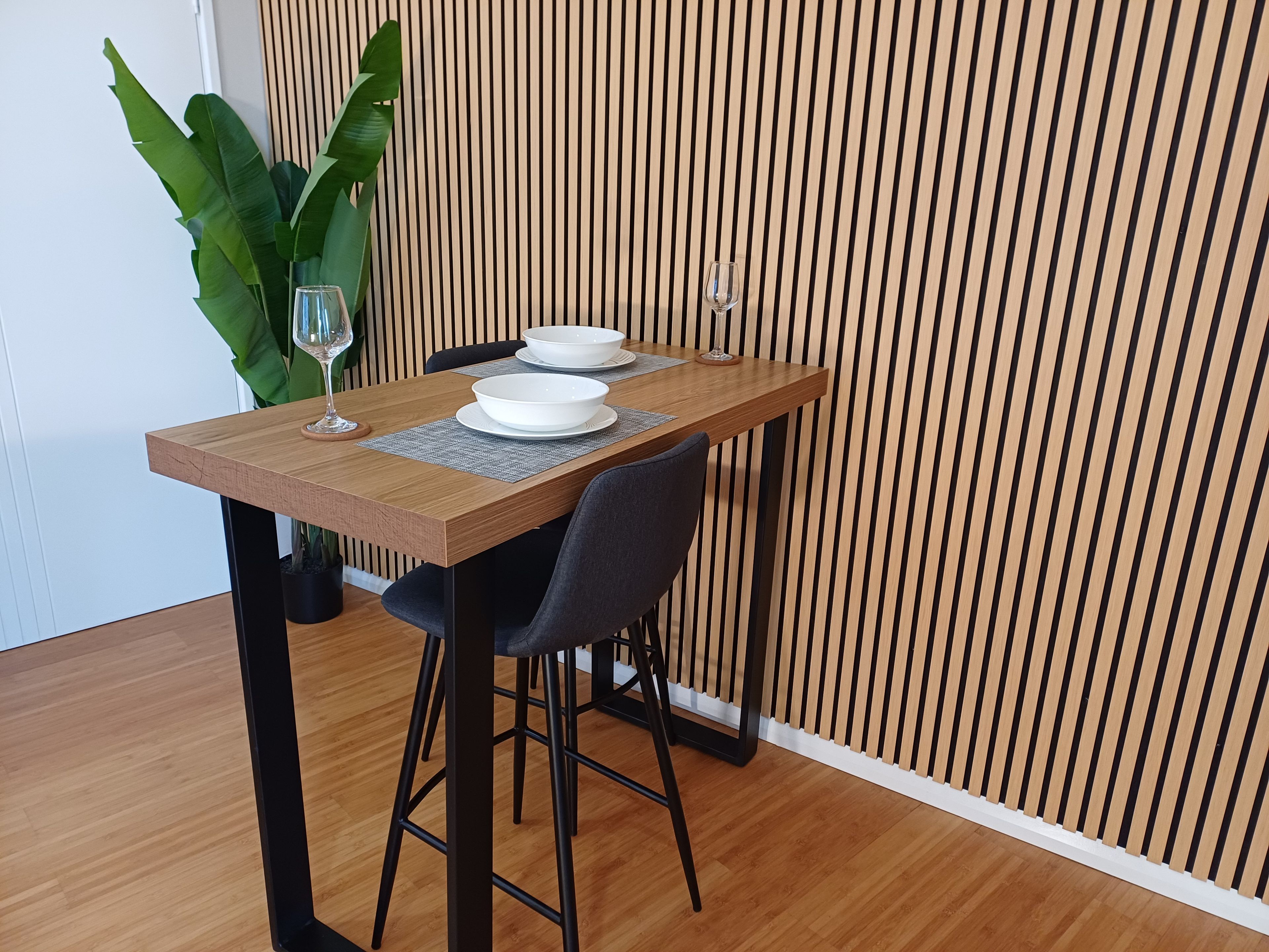 Une table à manger avec deux bols blancs, un verre à vin et une plante en pot.