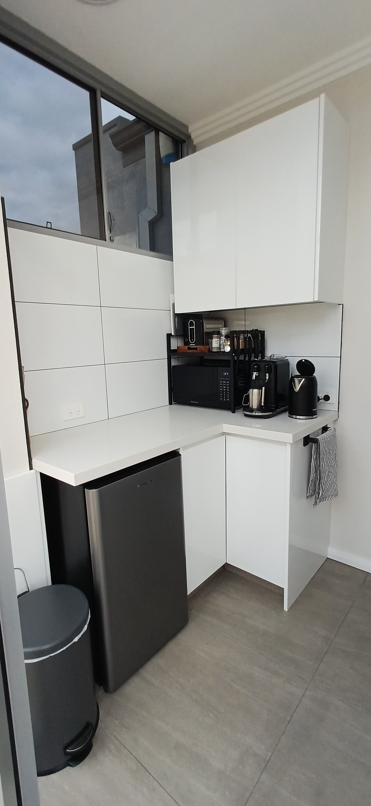 A modern kitchen with white cabinetry, a black coffee machine, and a dishwasher.