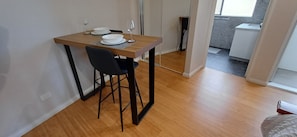 A small dining area with a wooden table, two white bowls, a glass, and a black chair. - Cosy Haven - Large Comfy Dwelling, Close to Beach, Shops and Golf Course (Madora Bay)