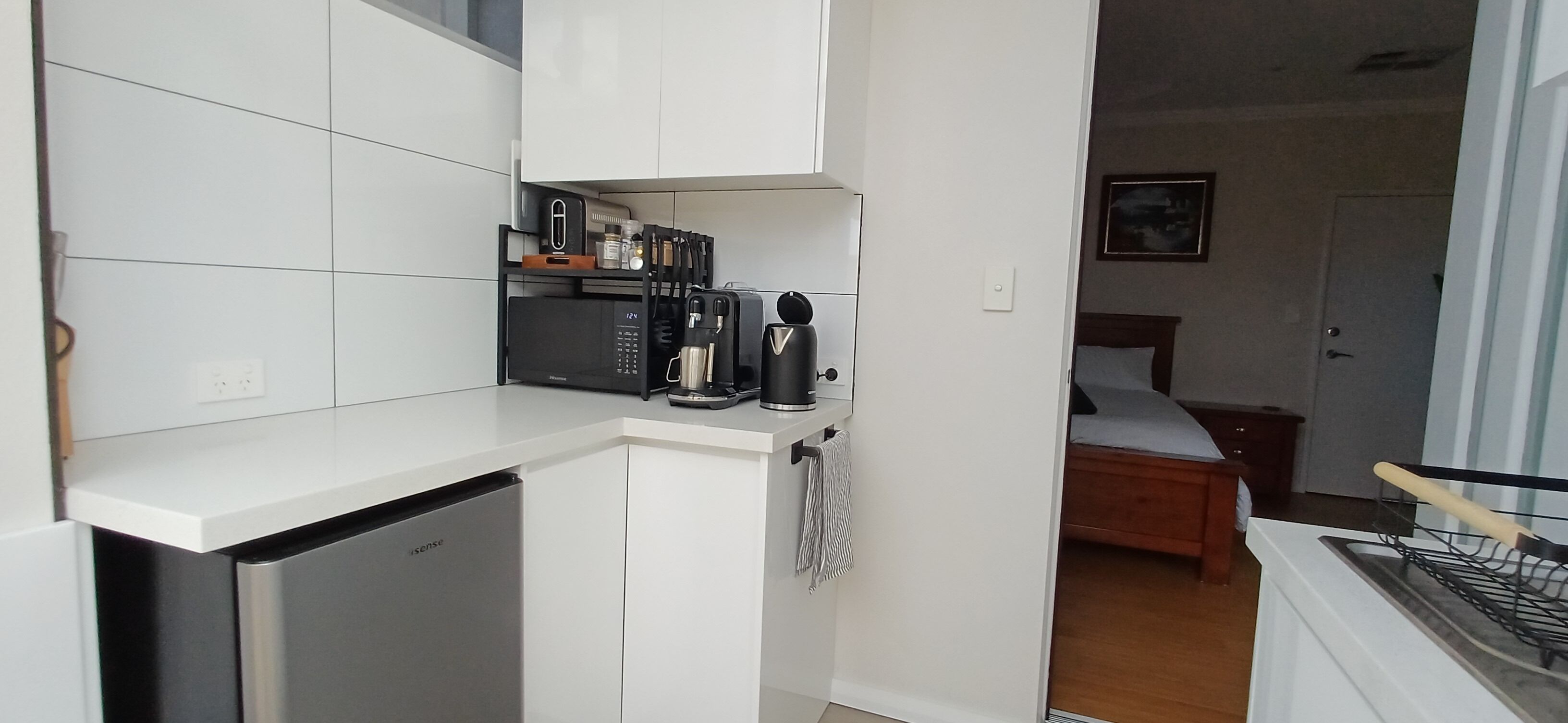 A compact kitchen with a built-in microwave, coffee maker, and toaster. A small refrigerator is visible to the left.