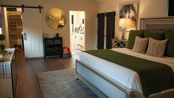 A bedroom with a bed, bedside table, lamp, and a view of the bathroom.