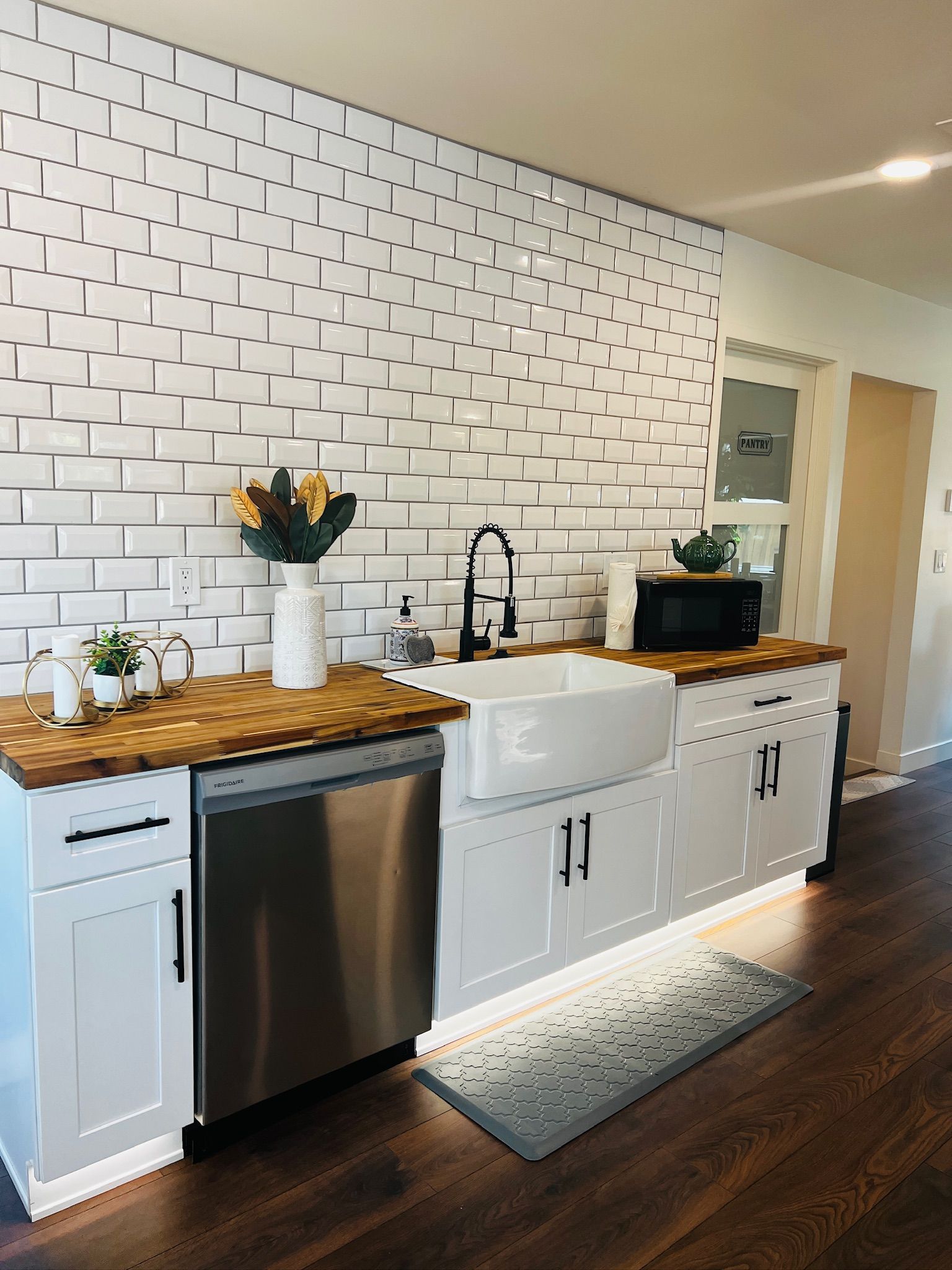 A modern kitchen with white subway tiles, stainless steel appliances, and wooden countertops.