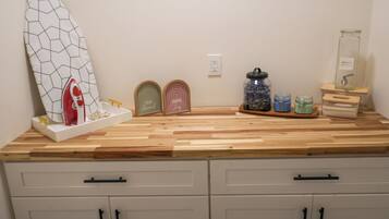A kitchen counter with a surfboard, jars, and a detergent bottle.