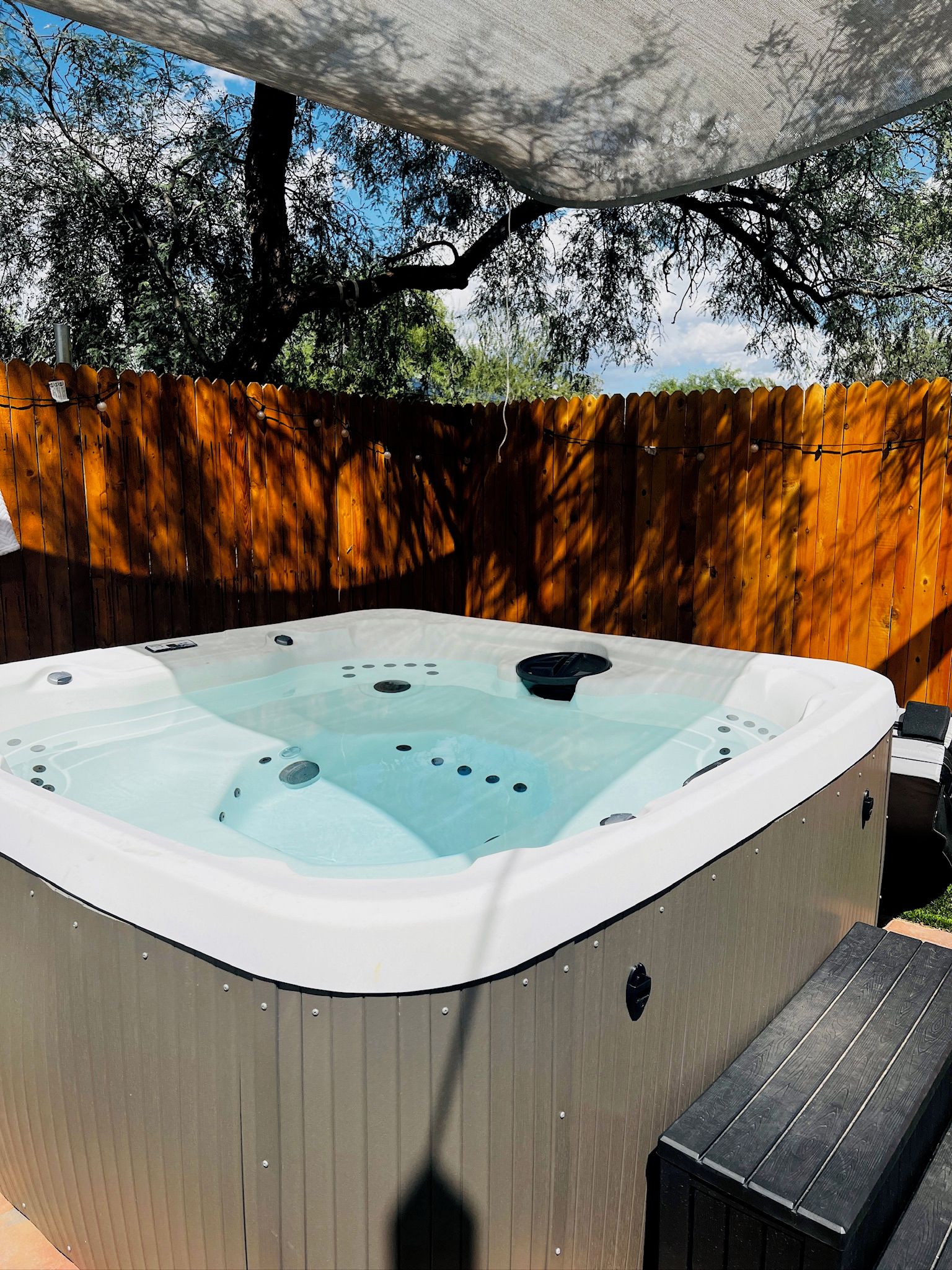 A hot tub with a wooden deck and a wooden fence in the background.