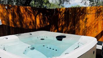 A hot tub with a wooden deck and a wooden fence in the background.
