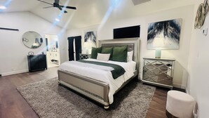 Quarto com cama grande, ventoinha no teto, espelho redondo e obras de arte nas paredes.