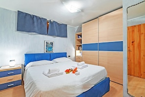 A bedroom with a bed, a nightstand, a wardrobe, and a window with curtains. - Appartamento I 2 Pini for 6 with Balcony, Sauze d'Oulx, Italy (Sauze d'Oulx)