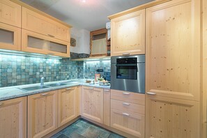A kitchen with wooden cabinets, a stainless steel oven, and a tiled backsplash. - Appartamento I 2 Pini for 6 with Balcony, Sauze d'Oulx, Italy (Sauze d'Oulx)