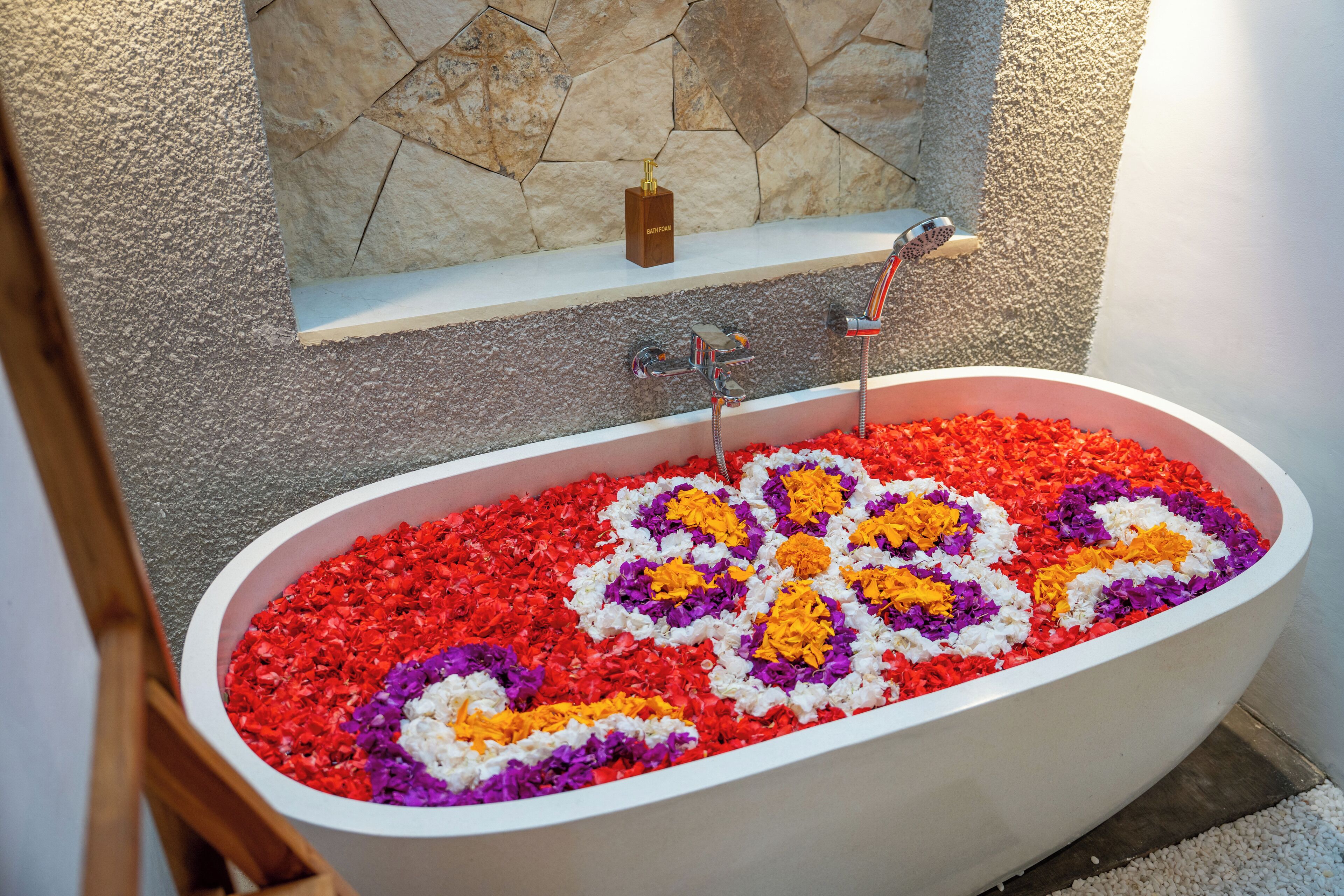 Una bañera llena de pétalos de flores multicolores.