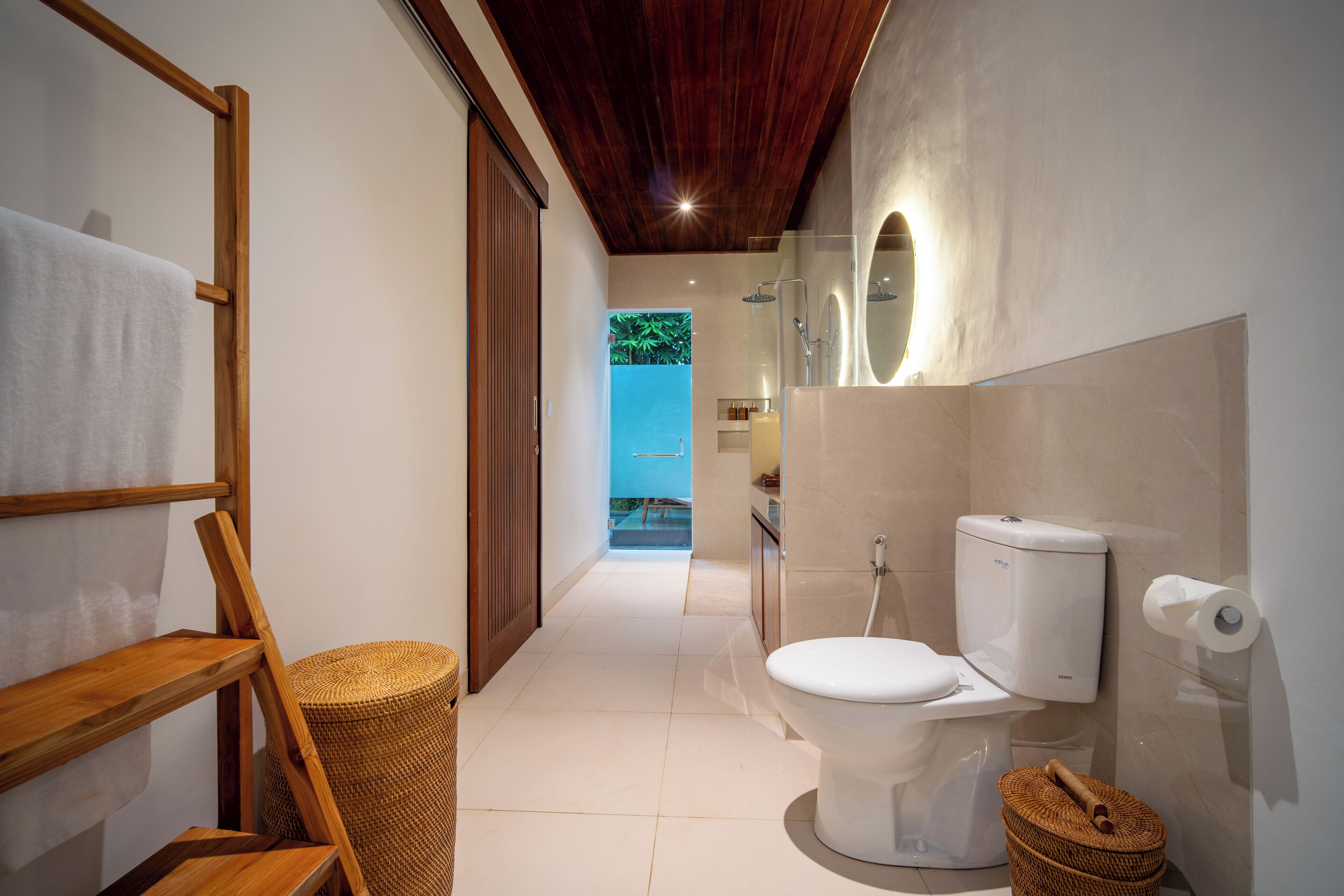 A modern bathroom with a wooden ceiling, a white toilet, a shower, and a view of a pool.